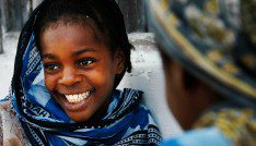 A girl smiles while playing a game with a friend in the village of Bwejuu on Zanzibar island, Tanzania, December 2, 2007. Picture taken December 2, 2007. REUTERS/Finbarr O'Reilly (TANZANIA) - GM1DWSSPAUAA
