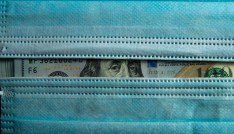 U.S. currency peeking out from behind two surgical masks